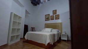 A bedroom with a bed, a nightstand, a chair, and a shelving unit. - Study Cádiz center, meters with air conditioning. Up to 5 people (Cádiz)