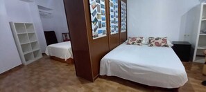 Ein Schlafzimmer mit einem Bett, einem kleinen Tisch, einem Kleiderschrank und einer Wand mit Fotos.