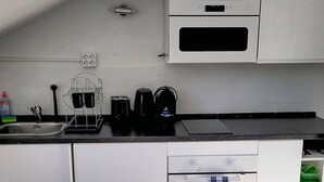 A compact kitchen with white cabinets, a built-in oven, a coffee maker, and a sink.