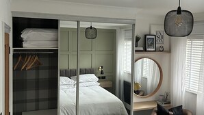 A bedroom with a bed, a wardrobe, a desk, a chair, and a hanging light fixture. - Freshly updated town house Carlisle City Centre (Carlisle)