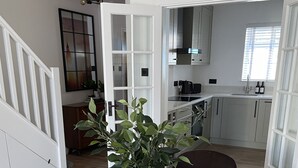 A dining area with a wooden table, a vase with green plants, and black chairs. - Freshly updated town house Carlisle City Centre (Carlisle)