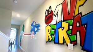 Um corredor com arte de graffiti colorida na parede, incluindo um grande número '1' e um sapo de desenho animado.