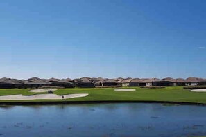 A golf course with bunkers and a pond.