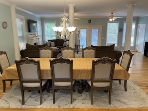 A dining room with a large table, six chairs, a chandelier, and a ceiling fan.