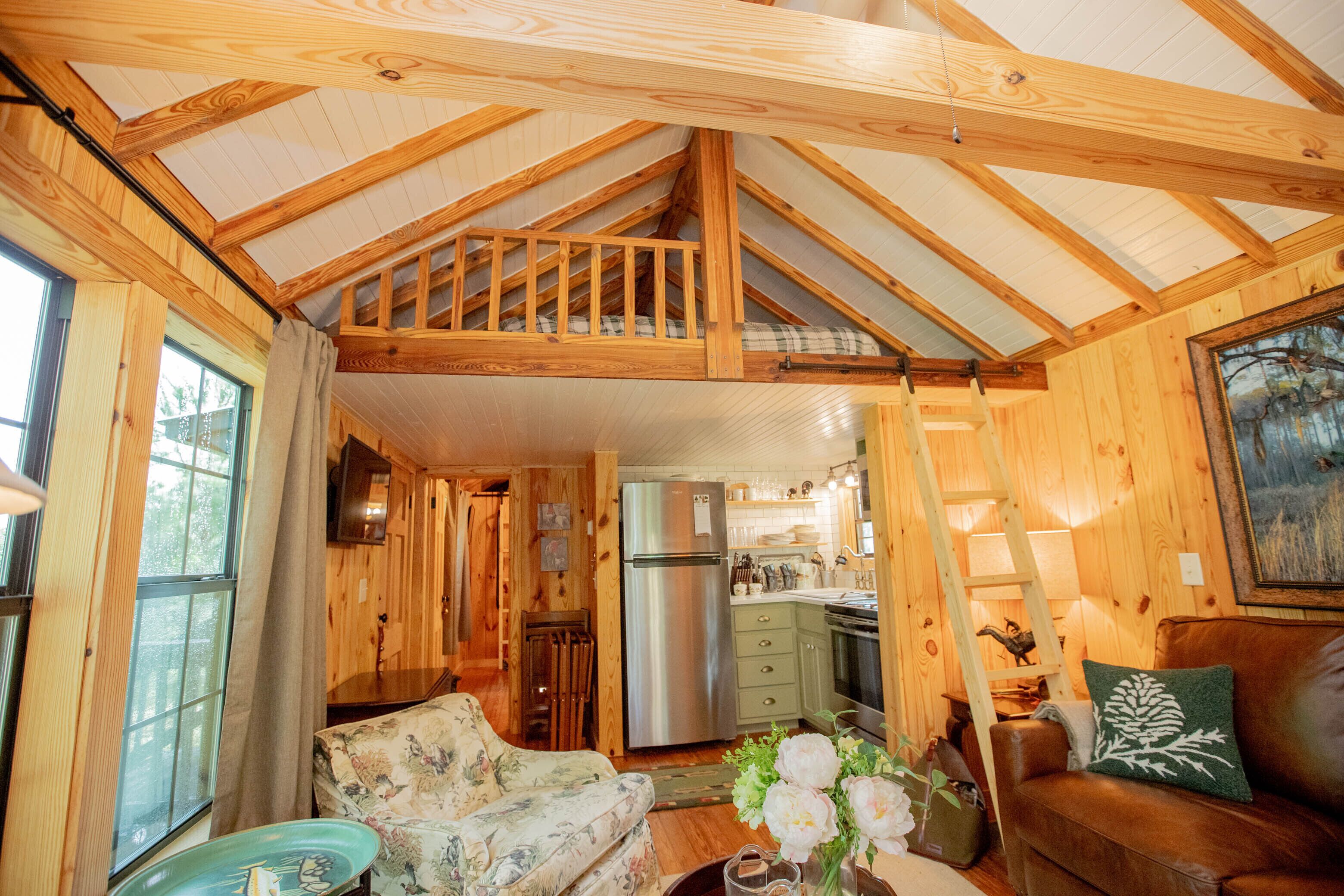 L’intérieur d’une cabane en bois comprend un coin repas, une cuisine et une chambre à l’étage, accessible par un escalier.
