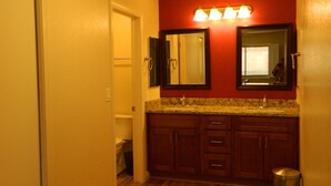 A bathroom with wooden flooring, a granite countertop, and a red accent wall. - Peaceful and tranquil townhouse for seniors  Heated pool/Spa gym. covered patio (Mesa)