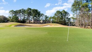 A golf course with a putting green, sand bunkers, and tall trees. - Condo in Legends Golf Course Resort  with a great Pub Next Door to the Unit (Myrtle Beach)