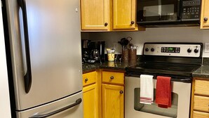 A kitchen with wooden cabinets, stainless steel appliances, and a tiled floor. - Condo in Legends Golf Course Resort  with a great Pub Next Door to the Unit (Myrtle Beach)