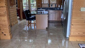 Una cocina amplia con armarios de madera, un refrigerador de acero inoxidable y un taburete de bar.