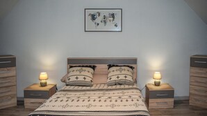 A bedroom with a bed, two bedside tables with lamps, a wooden headboard, and a framed world map on the wall. - 2 bedroom awesome home in Brélidy (Brélidy)