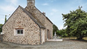 A stone building with a gabled roof, a small window, and a gravel driveway. - 2 bedroom awesome home in Brélidy (Brélidy)
