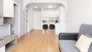 En moderne stue med en grå sofa, et træbord og et køkken i baggrunden.