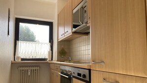 Una cocina compacta con armarios de madera, microondas integrado y lavavajillas.