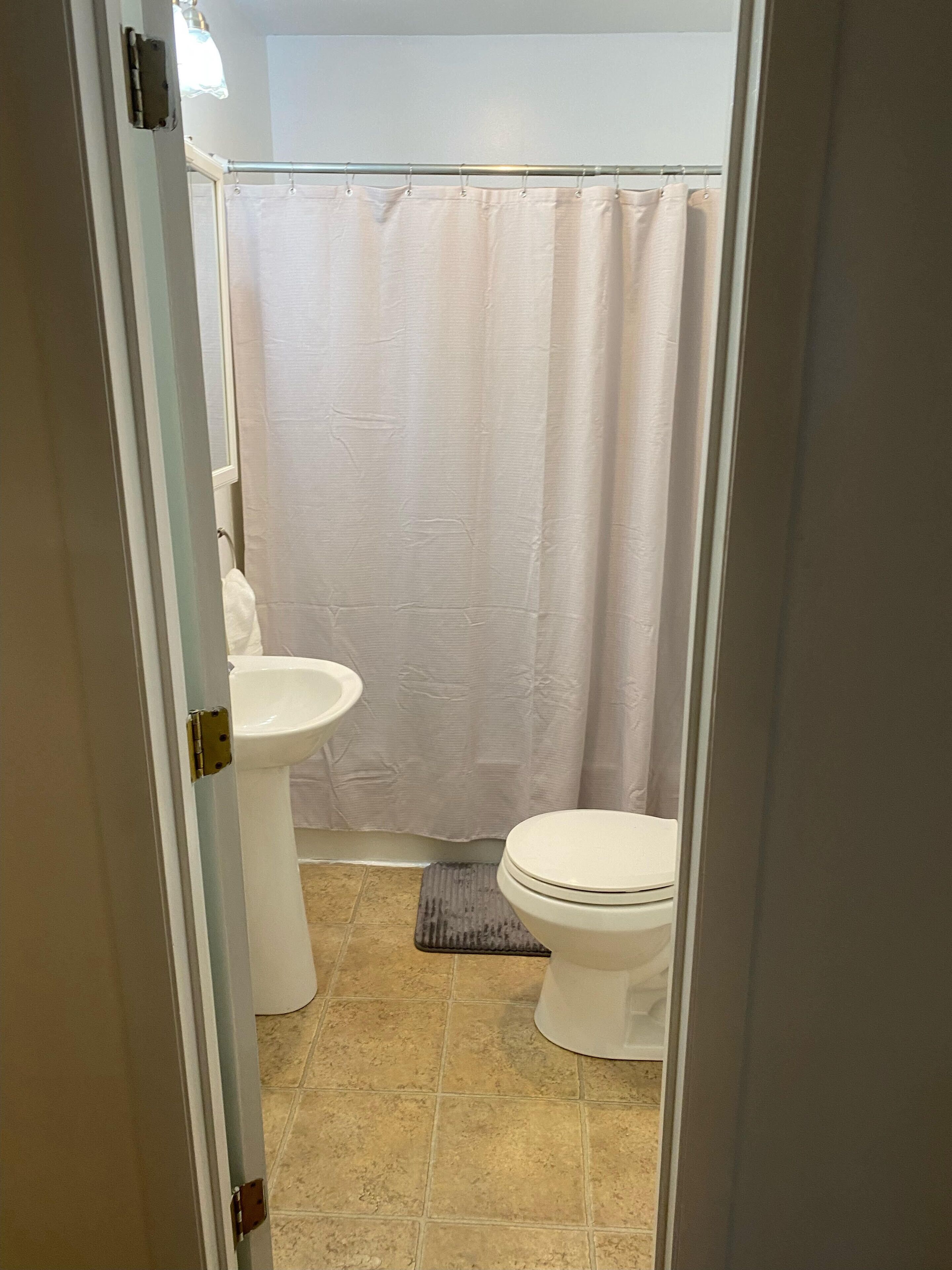 Un baño con inodoro, lavamanos y cortina de ducha.