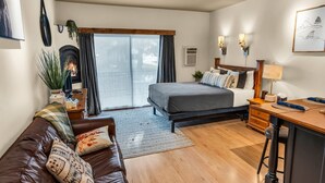 Um quarto moderno com cama, escrivaninha de madeira, sofá de couro e lareira.
