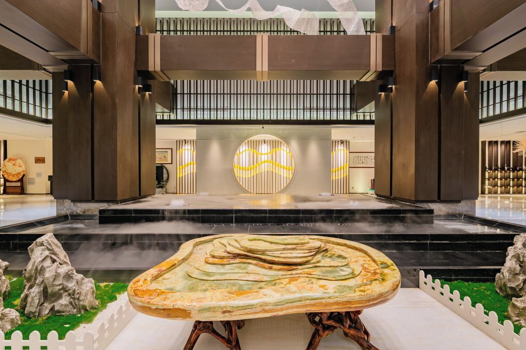 A spacious lobby with a central fountain, a high ceiling with vertical lines, and a modern design.