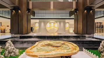 A spacious lobby with a central fountain, a high ceiling with vertical lines, and a modern design.