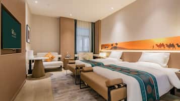 A hotel room with a large bed, two bedside tables, a sofa, a desk, and a wall-mounted TV.