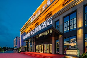 A hotel with a modern facade, illuminated signage, and a prominent entrance.