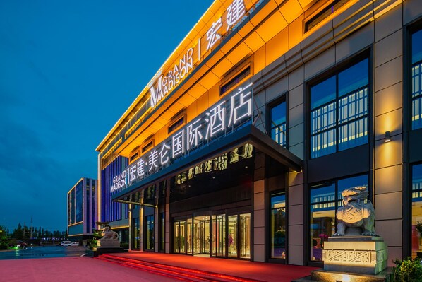 A hotel with a modern facade, illuminated signage, and a prominent entrance.