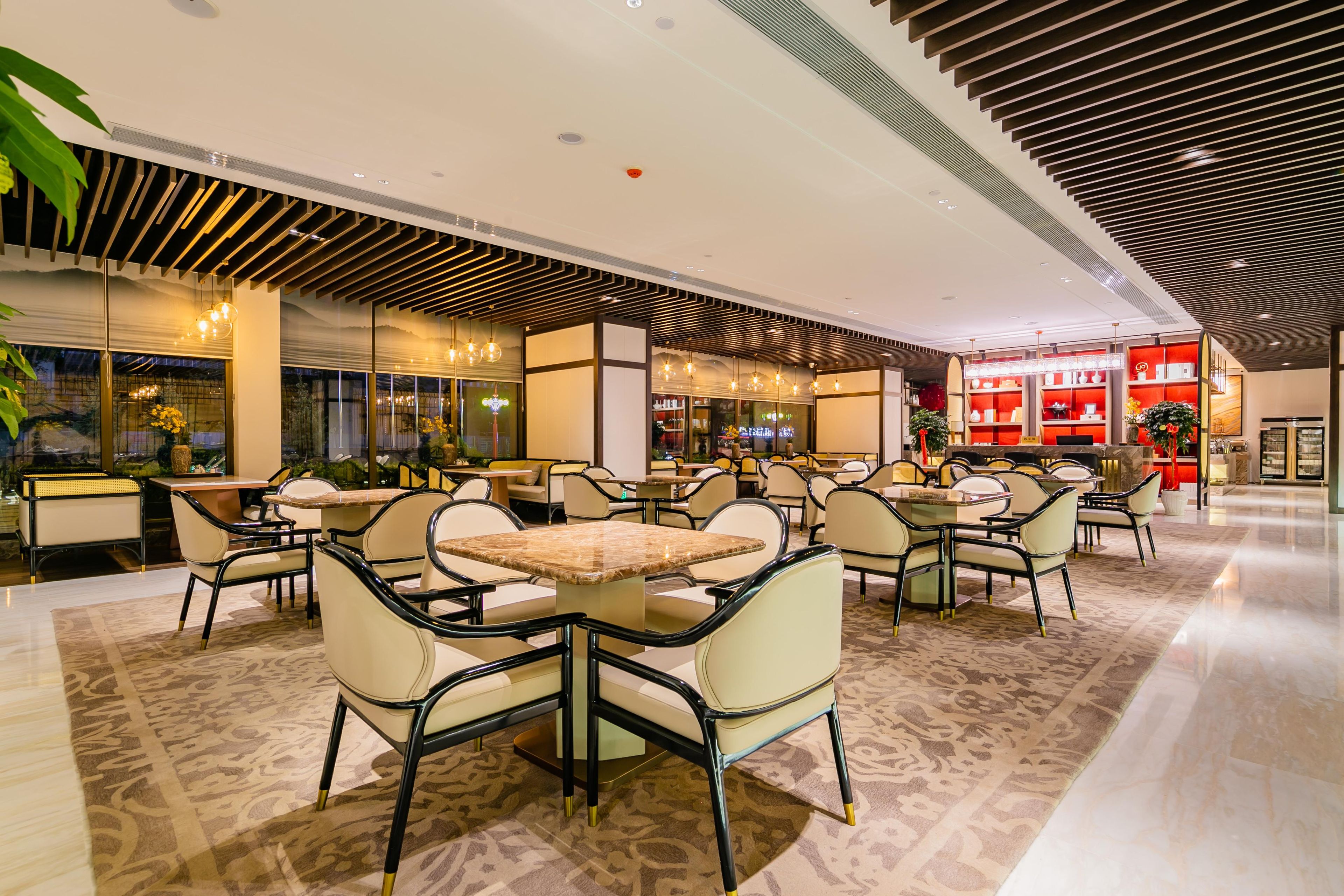 A spacious indoor area with multiple seating arrangements, including tables and chairs, and a visible store with shelves in the background.