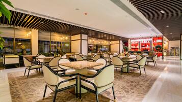 A spacious indoor area with multiple seating arrangements, including tables and chairs, and a visible store with shelves in the background.