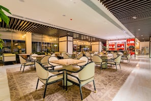 A spacious indoor area with multiple seating arrangements, including tables and chairs, and a visible store with shelves in the background.