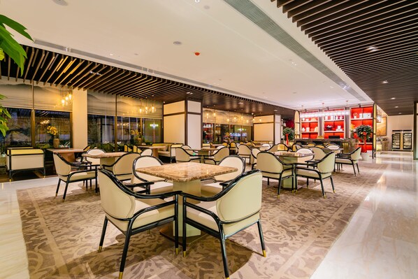 A spacious indoor area with multiple seating arrangements, including tables and chairs, and a visible store with shelves in the background.