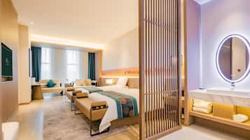 A hotel room with a bed, seating area, and a bathroom with a mirror and sink.