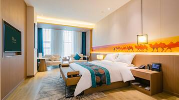Een moderne hotelkamer met een groot bed, een bureau met een computer, een televisie en een kunstwerk aan de muur.