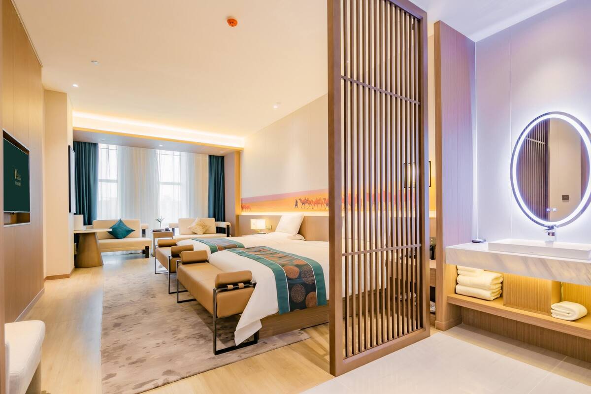 Ein Hotelzimmer mit Bett, Sitzecke und Bad mit Spiegel und Waschbecken.