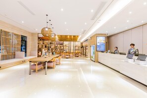 A modern hotel lobby with a reception desk, seating area, and a large digital display. - Hanting Premium Hotel (Hangzhou)