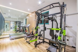 A gym with various exercise equipment, a treadmill, and a mirrored wall.