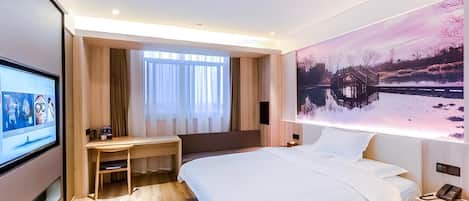Une chambre d’hôtel moderne, dotée d’un grand lit, d’un bureau, d’une télévision et d’un tableau représentant un paysage hivernal.