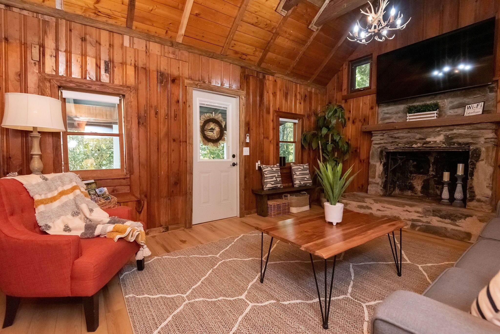 Acogedor interior de cabaña con detalles de madera, una chimenea, un televisor y un espacio de estar cómodo.