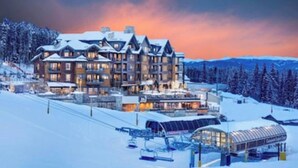 A large, multi-story lodge with a ski lift and snow-covered surroundings.