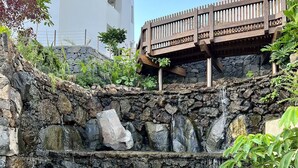 Uma cascata de pedra com um deck de madeira acima.