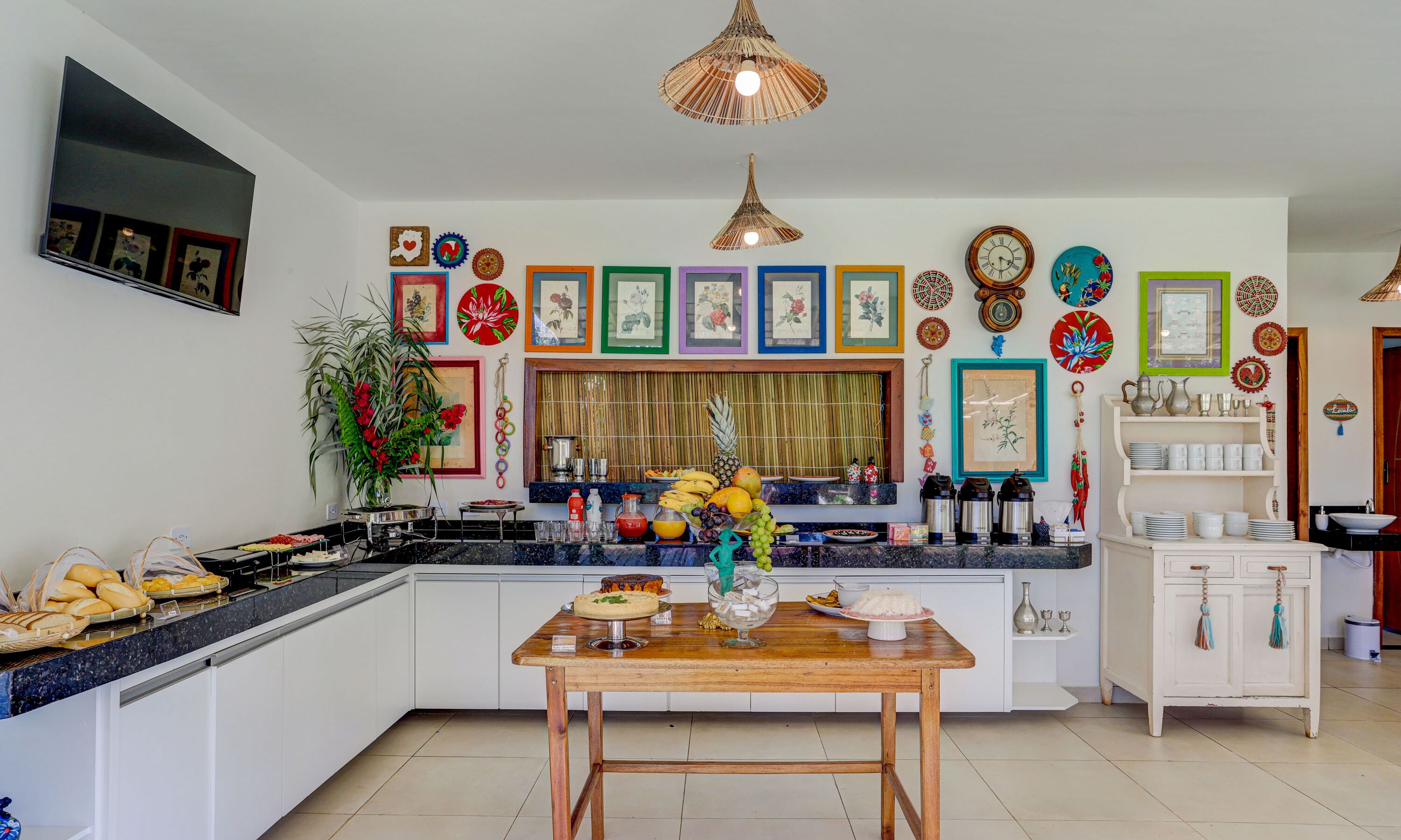 A modern kitchen with a central island, white cabinetry, and a variety of decorative plates and artwork on the walls.