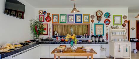 A modern kitchen with a central island, white cabinetry, and a variety of decorative plates and artwork on the walls.