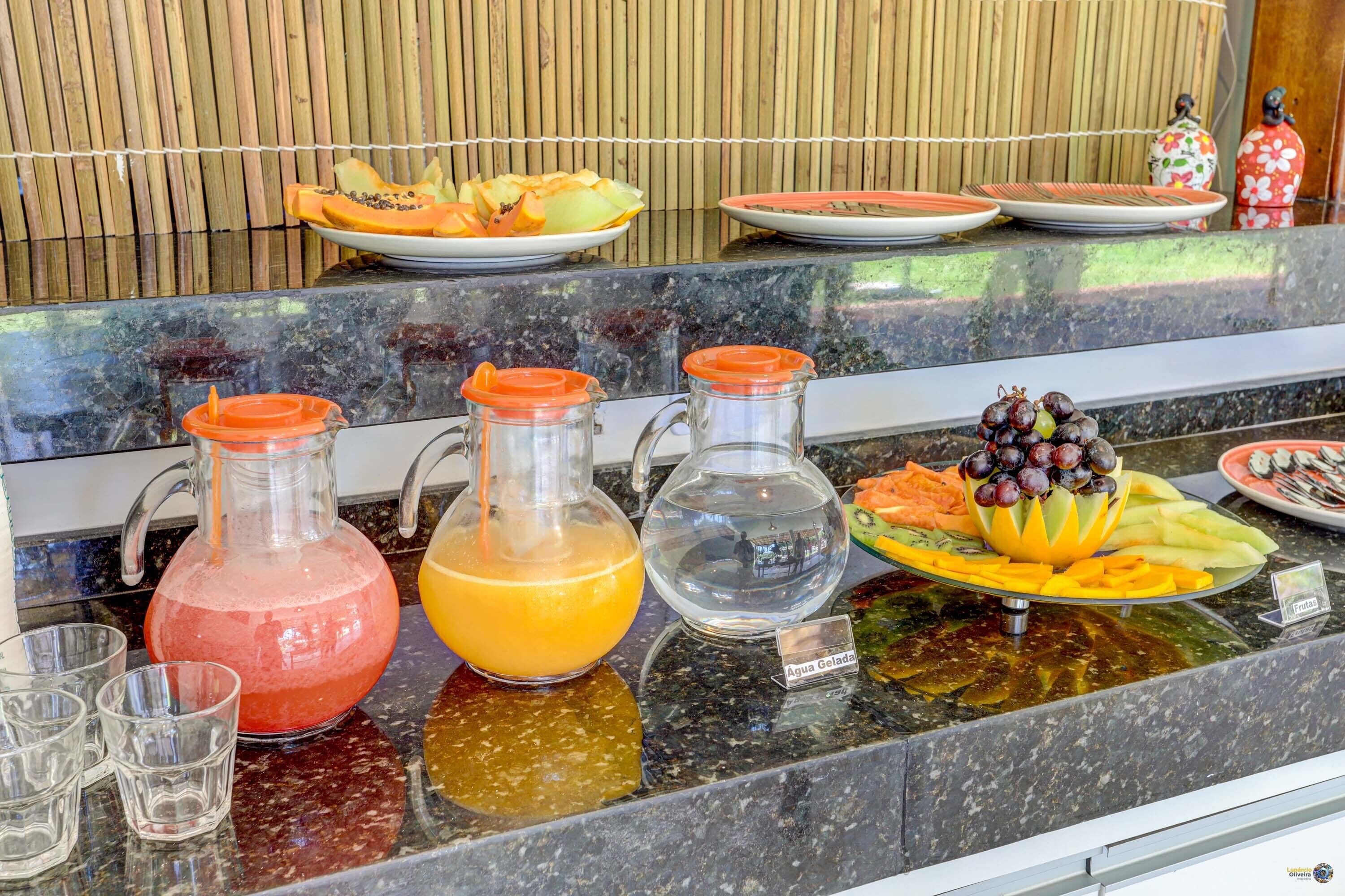 A buffet with various fruits, juices, and a sign indicating 'Agua Gelada'.