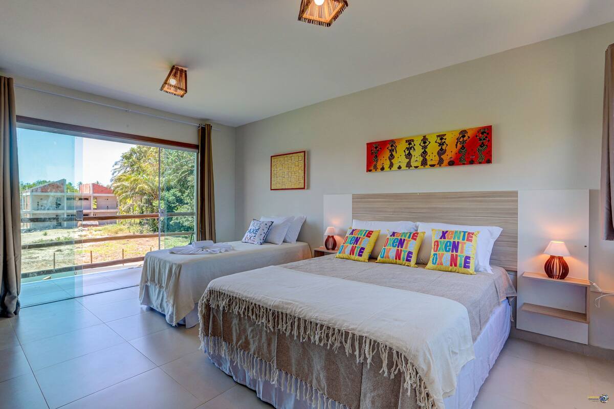 Una habitación de hotel con dos camas, un ventanal grande, un cuadro y una lámpara.