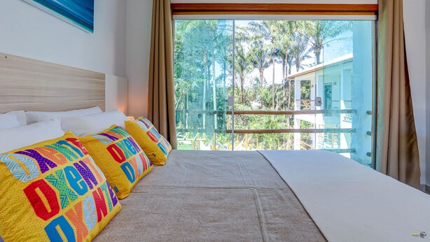 Habitación de hotel con una cama grande, vista a árboles y edificios, y un cuadro en la pared.