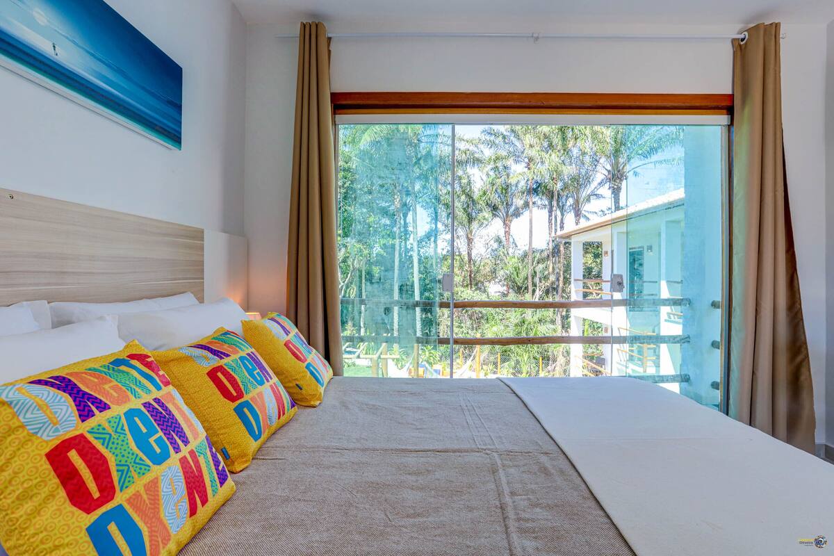 Habitación de hotel con una cama grande, vista a árboles y edificios, y un cuadro en la pared.