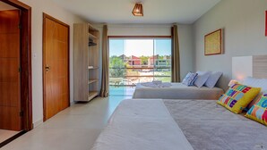 Habitación de hotel con dos camas, un ventanal con vistas, una puerta de madera y una lámpara en el techo.