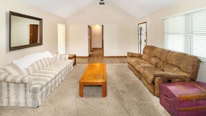 A living room with a striped sofa, a brown sofa, a wooden coffee table, and a purple suitcase. - Comfort and Charm Highly Recommended (Newburgh)