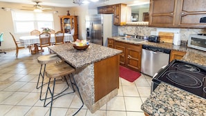A kitchen with granite countertops, wooden cabinets, a stainless steel refrigerator, a dishwasher, and a bar area with stools. - Comfort and Charm Highly Recommended (Newburgh)