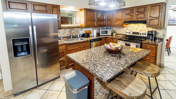 A modern kitchen with stainless steel appliances, wooden cabinets, granite countertops, and a central island with stools. - Comfort and Charm Highly Recommended (Newburgh)