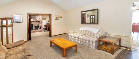 A spacious living room with a fireplace, a sofa, a coffee table, and a mirror.