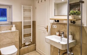 Une salle de bain comprenant des toilettes, un lavabo, un porte-serviettes et un espace douche.
