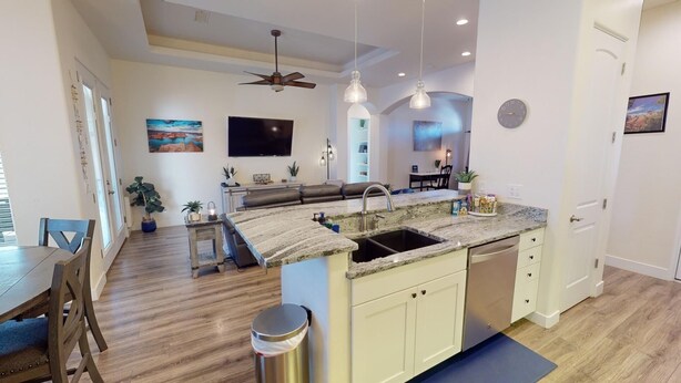 A modern kitchen with a granite countertop, a built-in dishwasher, and a dining area with a wooden table and chairs. - Quiet, Cozy Three Bedroom Two Bath Home, Great Location (Page)
